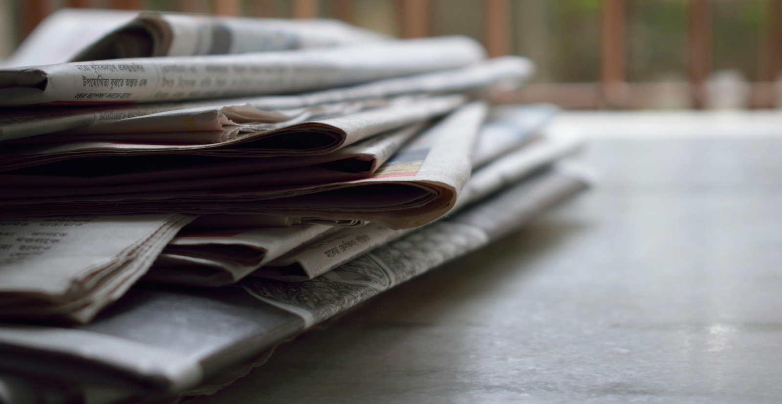 A stack of newspapers on a wooden table
